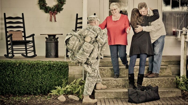Soldier and his spouse are greeted by family with hugs at Christmas