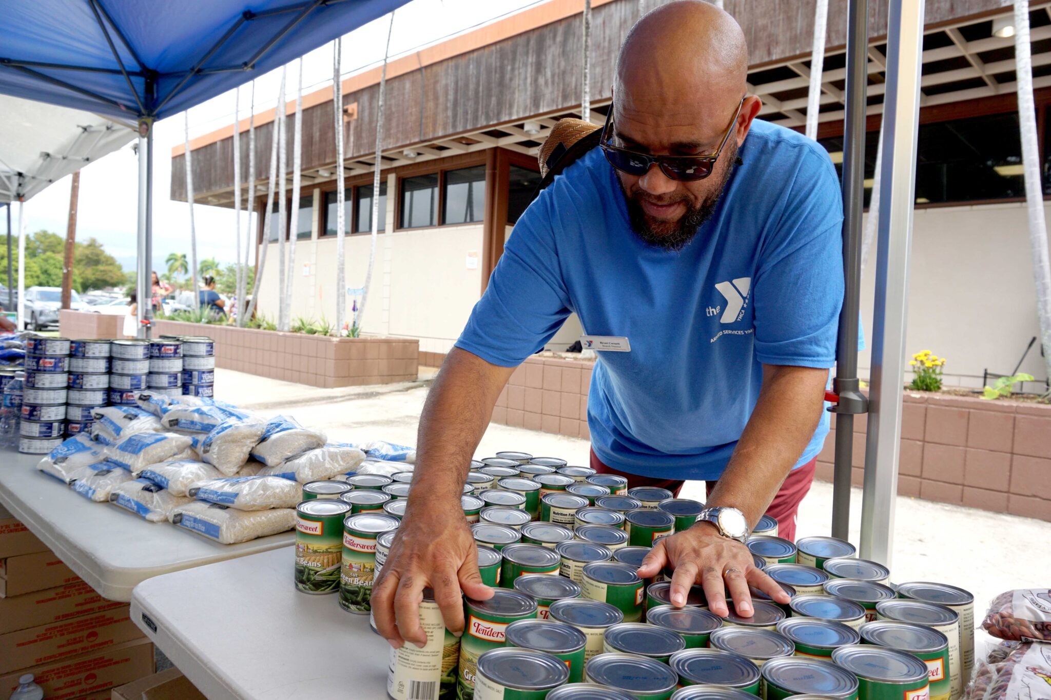 ASYMCA Hawaii employee stacking food items for the Ohana Open Market event happening at Joint Base Pearl Harbor Hickam.